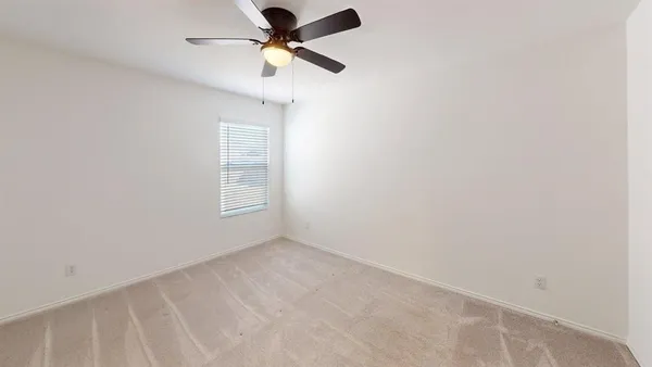 an empty room with a window and a fan