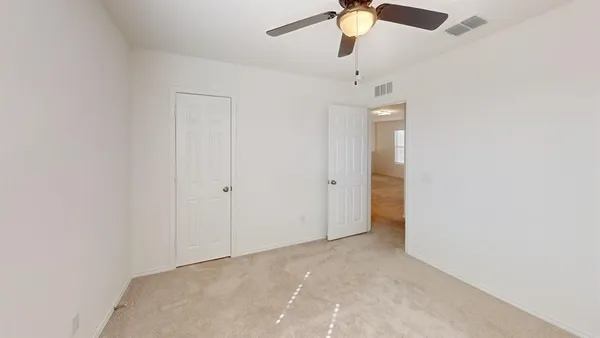 an empty room with a chandelier fan and closet