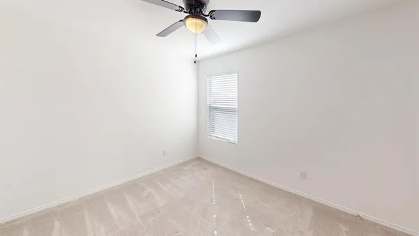 an empty room with a window and a fan