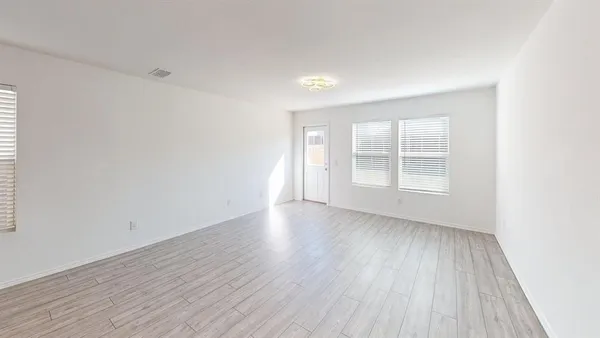 an empty room with wooden floor and windows