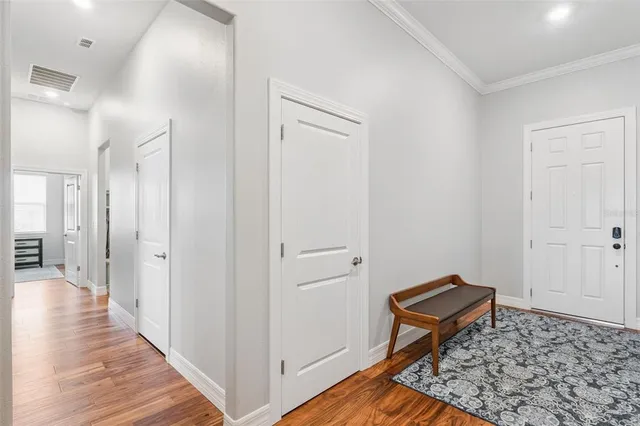 a view of a hallway with wooden floor and a bathroom