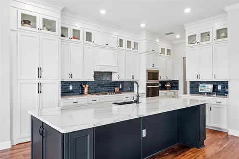 a kitchen with stainless steel appliances kitchen island granite countertop a sink dishwasher and a stove with wooden floor