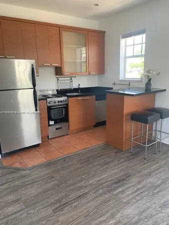 a kitchen with granite countertop a stove a sink and a refrigerator