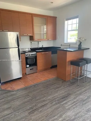 a kitchen with granite countertop a stove a sink and a refrigerator