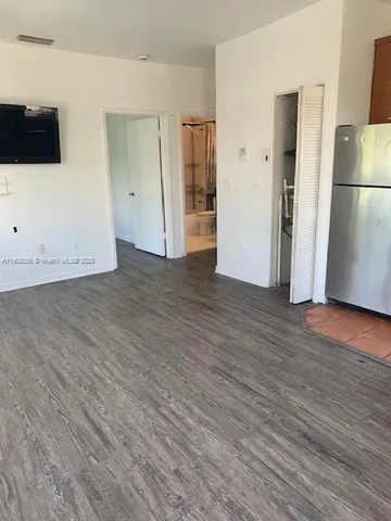 a view of empty room with wooden floor and refrigerator