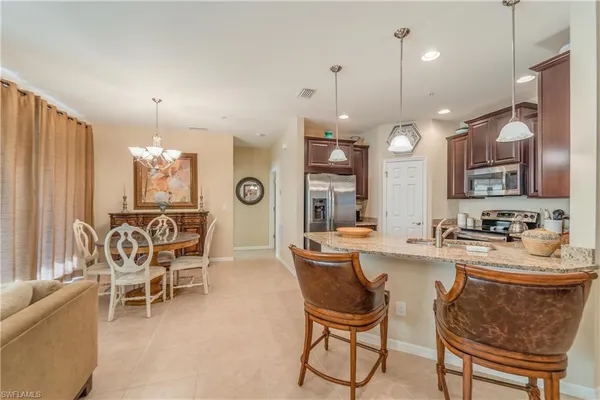 a kitchen with stainless steel appliances kitchen island granite countertop a sink and a refrigerator