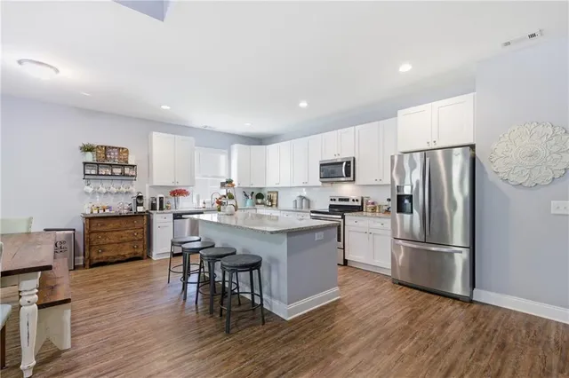 a kitchen with stainless steel appliances granite countertop a stove top oven a sink a microwave and cabinets