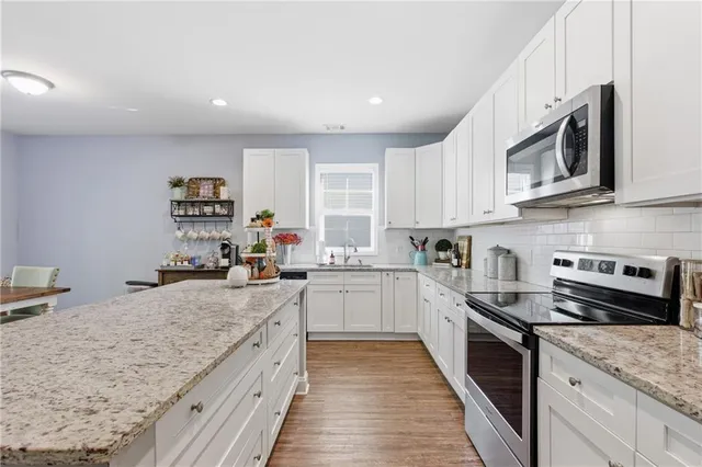 a kitchen with stainless steel appliances granite countertop a sink dishwasher and cabinets with wooden floor