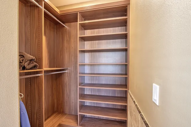 a view of walk in closet with clothes and shoes