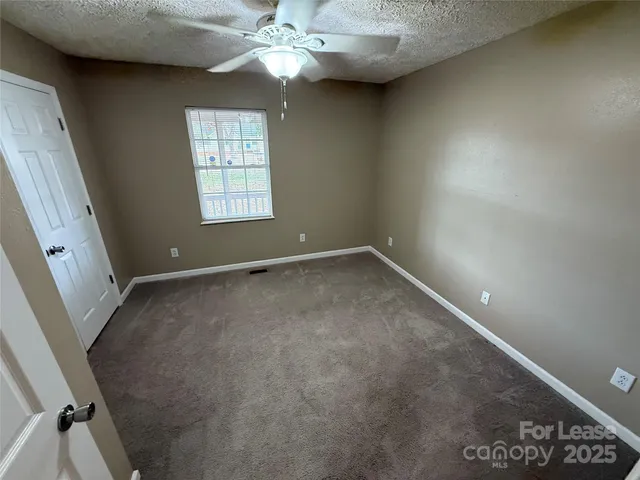 en empty room with windows and chandelier fan
