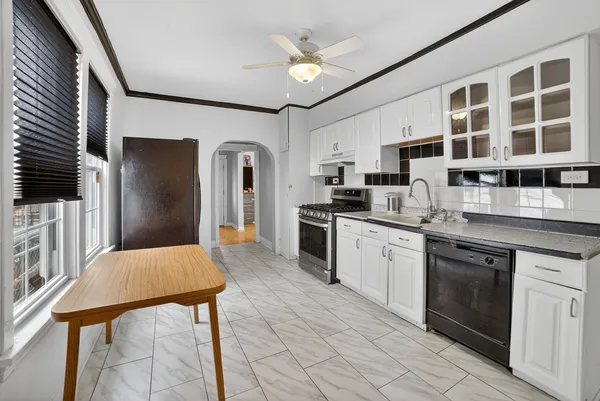 a kitchen with stainless steel appliances kitchen island granite countertop a refrigerator a sink dishwasher a stove and white cabinets with wooden floor
