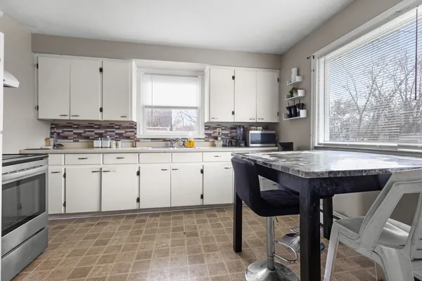 a kitchen with stainless steel appliances granite countertop a stove a sink dishwasher and white cabinets with wooden floor