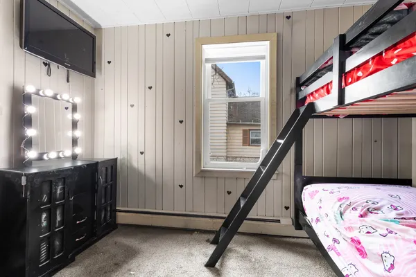a bedroom with a bed a dresser and potted plants on the dresser
