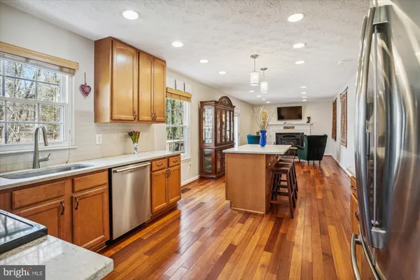 a large kitchen with stainless steel appliances granite countertop a refrigerator a sink dishwasher a stove and white countertops with wooden floor