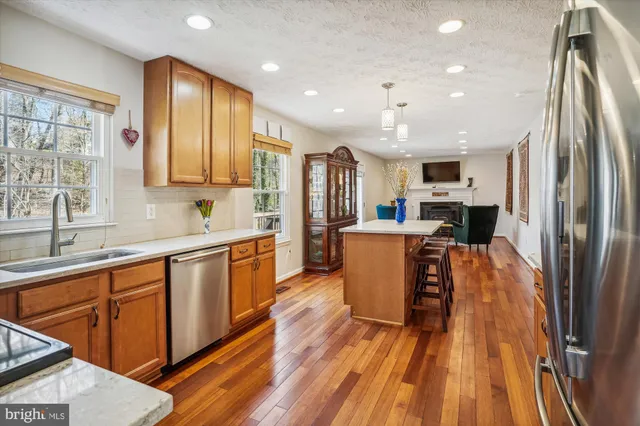 a large kitchen with stainless steel appliances granite countertop a refrigerator a sink dishwasher a stove and white countertops with wooden floor