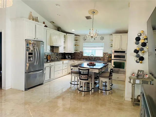 a kitchen with stainless steel appliances kitchen island granite countertop a table chairs and a refrigerator