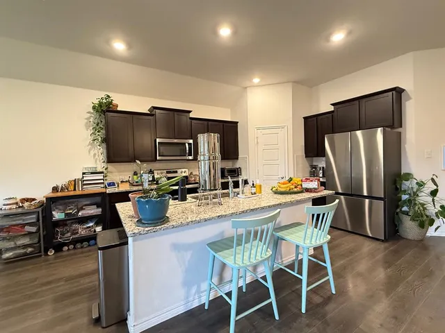 a kitchen with stainless steel appliances a refrigerator a stove a dining table and chairs