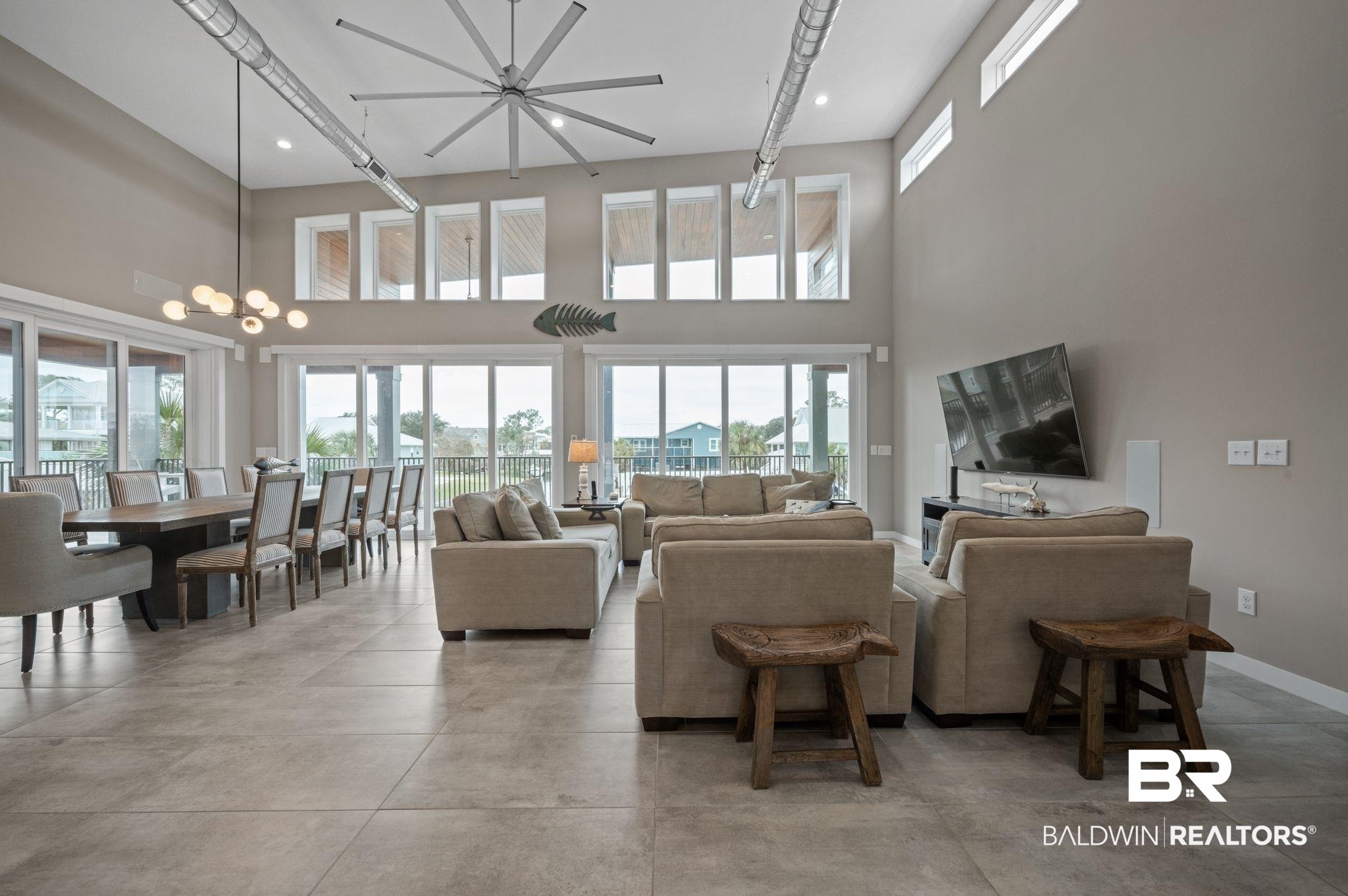 3840 Cotton Way Orange Beach, AL 36561 - Photo 5 of 75 Living room featuring ceiling fan with notable chandelier, plenty of natural light, and a high ceiling