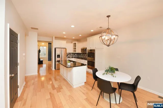 a kitchen with stainless steel appliances kitchen island granite countertop a table chairs and a wooden floor