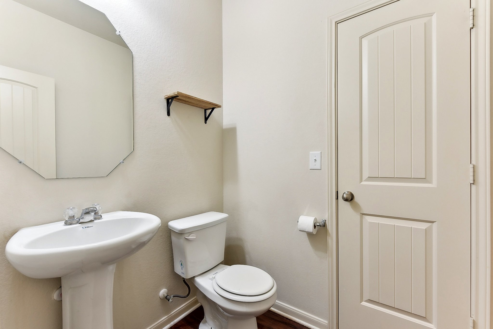 310 Potters Peak Way Georgetown, TX 78626 - Photo 9 of 21 Pedestal sink with chrome faucet, octagonal wall mirror, and wood-finish flooring