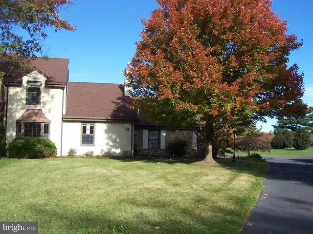 a front view of house with yard and trees in the background