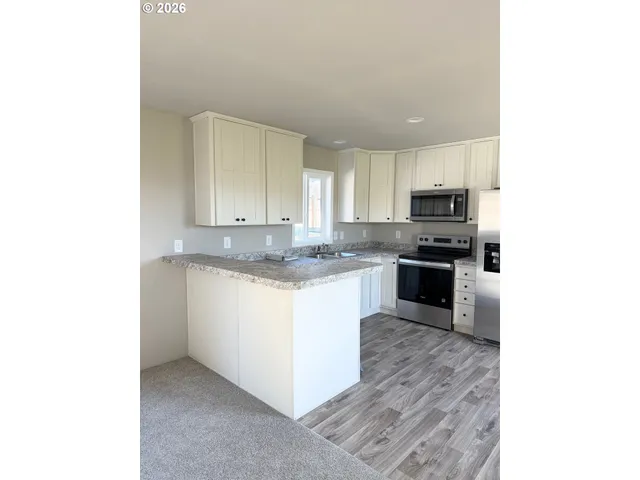 a kitchen with wooden floors white cabinets and stainless steel appliances