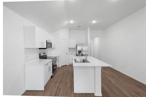 a kitchen with stainless steel appliances a sink dishwasher stove refrigerator and white cabinets with wooden floor