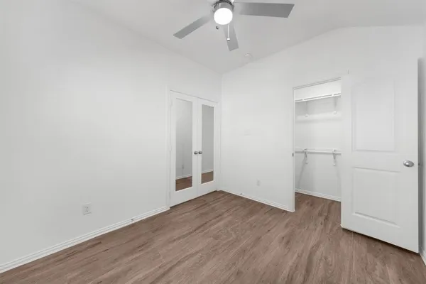 an empty room with wooden floor cabinet and windows