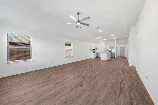 a view of empty room with wooden floor and ceiling fan