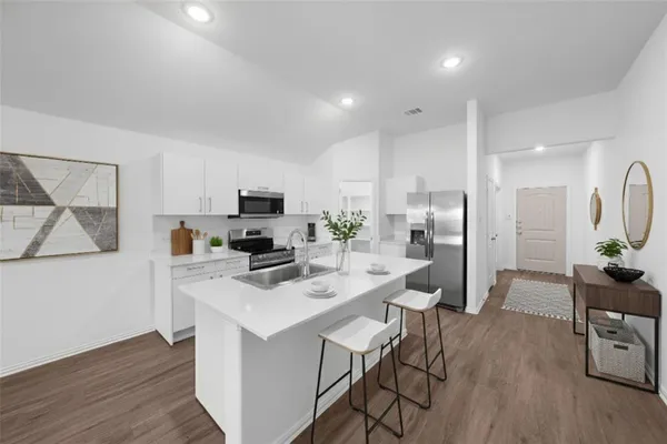 a kitchen with a refrigerator a stove top oven a sink dishwasher and white cabinets with wooden floor