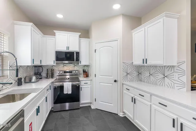 a kitchen with white cabinets sink and stainless steel appliances