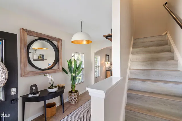 a view of a hallway with entryway wooden floor a fireplace and a chandelier