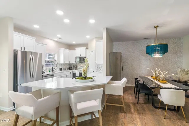 a dining room with stainless steel appliances kitchen island granite countertop a dining table chairs and a refrigerator