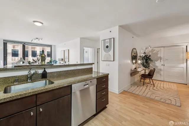 a living room with stainless steel appliances granite countertop a sink and wooden floor