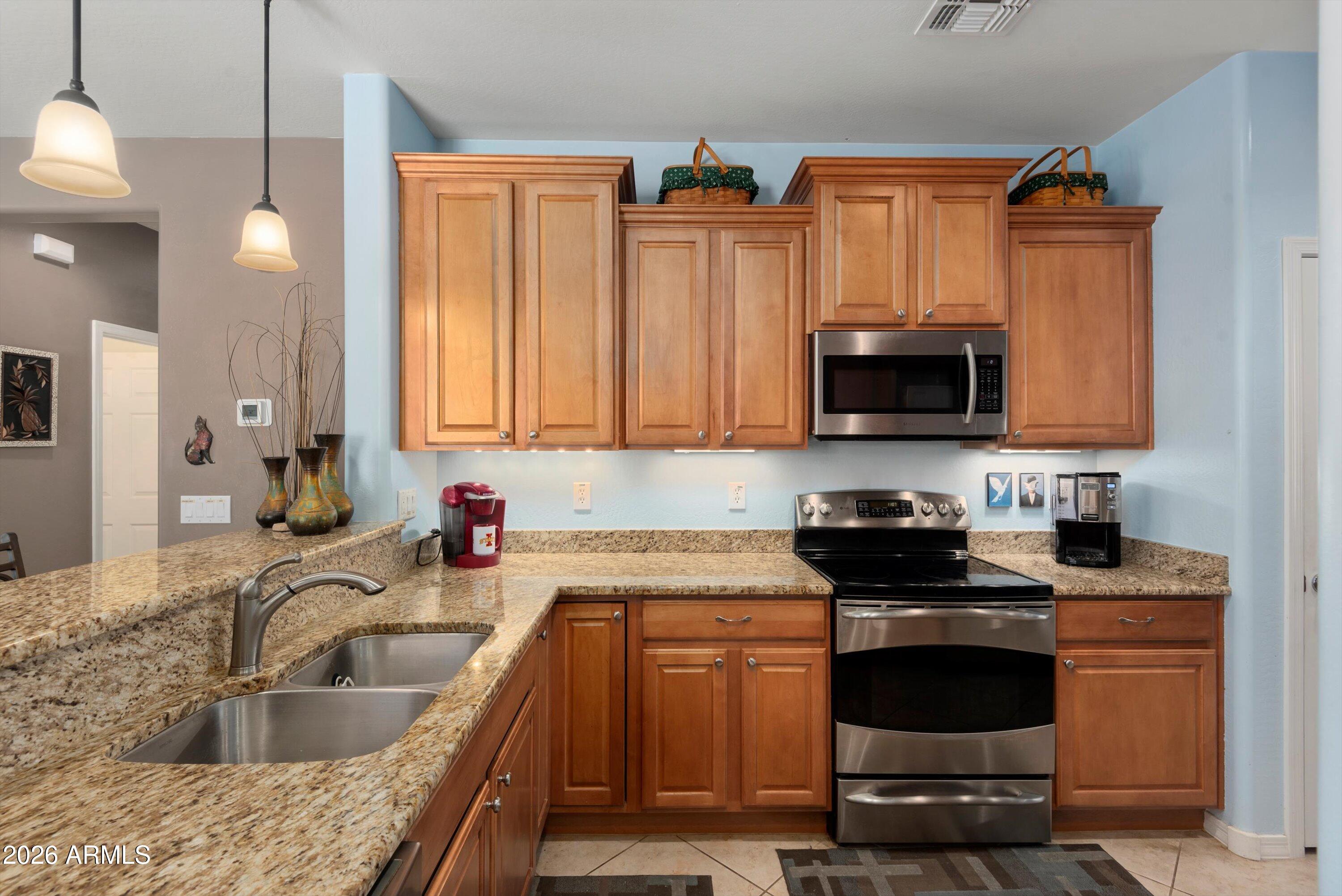 21613 North 261st Avenue Buckeye, AZ 85396 - Photo 5 of 52 a kitchen with granite countertop a sink dishwasher stove and microwave with wooden floor