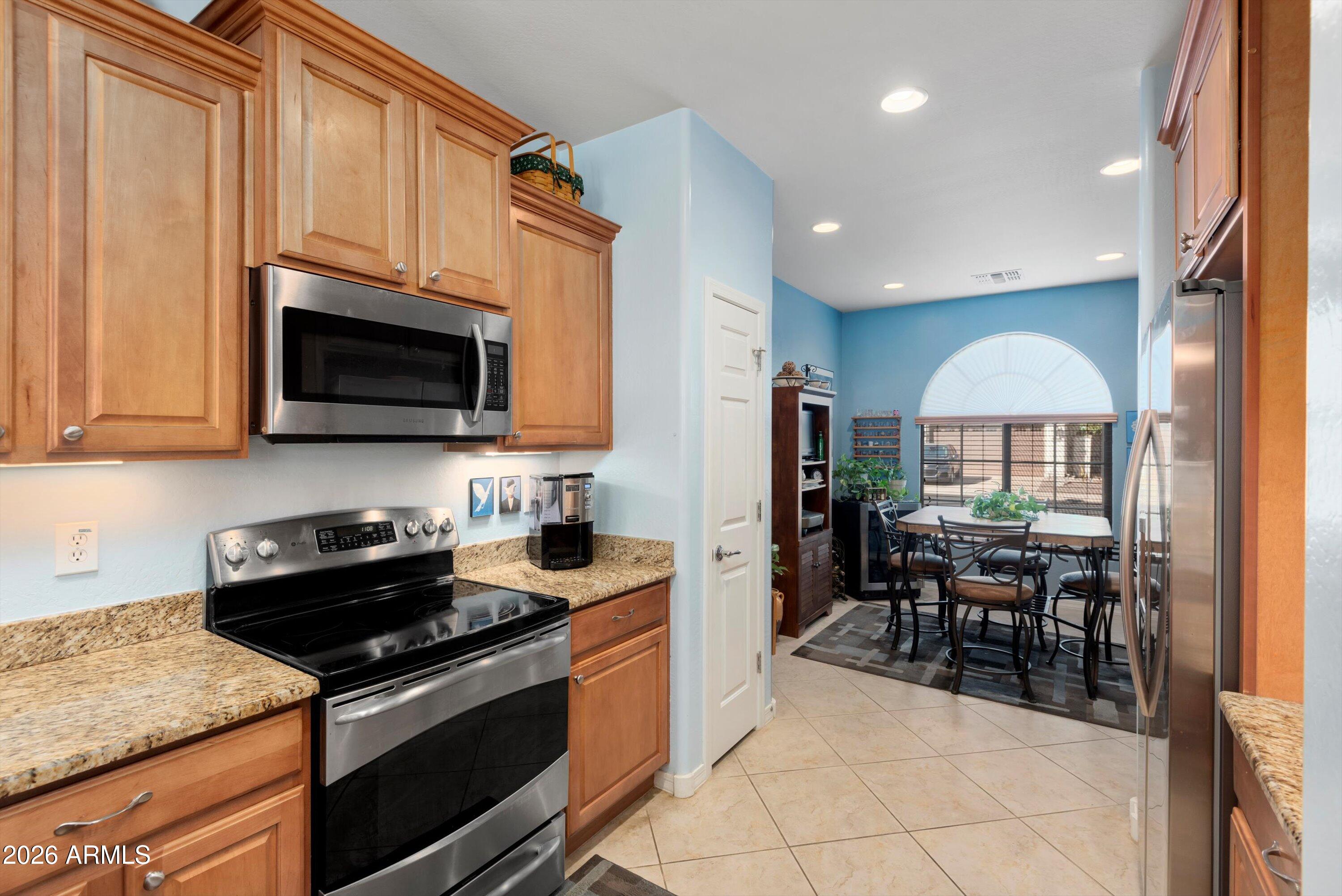 21613 North 261st Avenue Buckeye, AZ 85396 - Photo 6 of 52 a kitchen with stainless steel appliances granite countertop a stove top oven a sink dishwasher a dining table and chairs with wooden floor