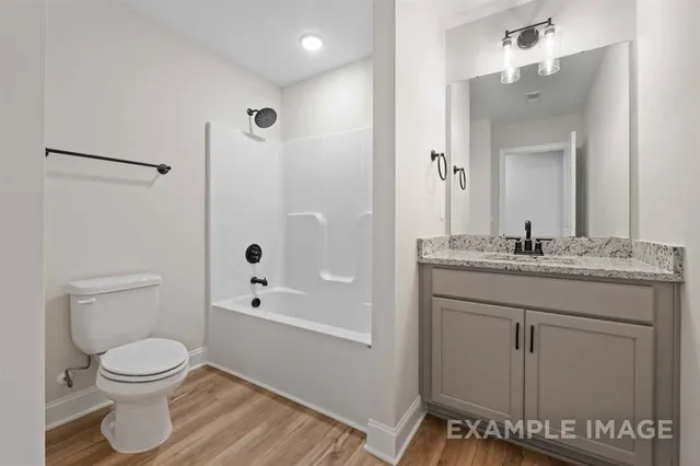 a bathroom with a granite countertop sink a toilet and shower