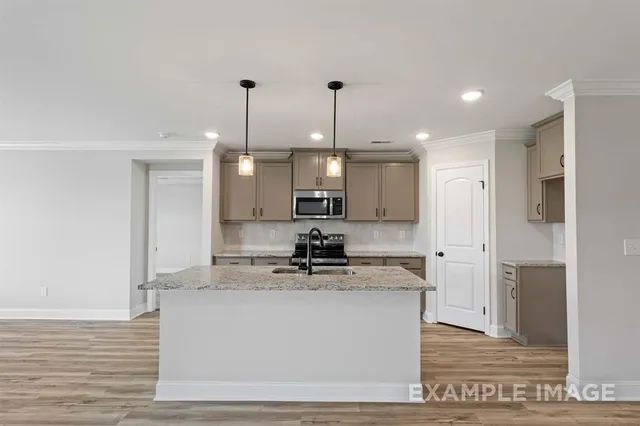 a kitchen with kitchen island granite countertop a sink a counter space appliances and cabinets