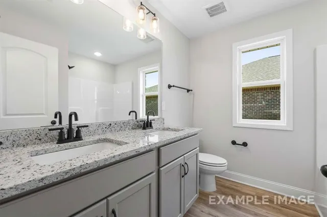 a bathroom with a granite countertop sink a toilet and mirror