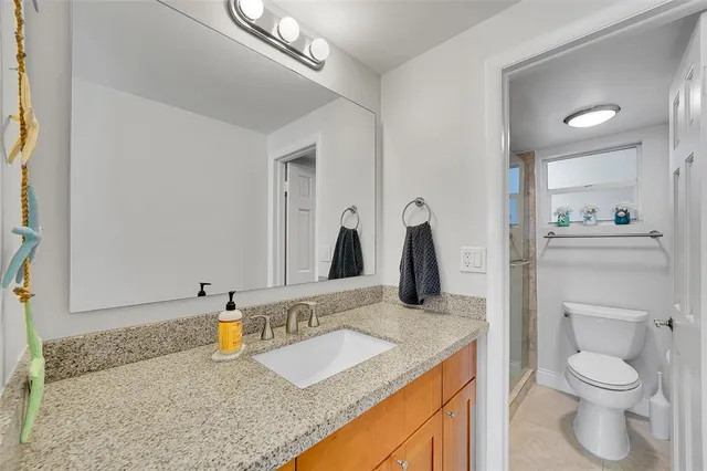 a bathroom with a granite countertop sink and a toilet
