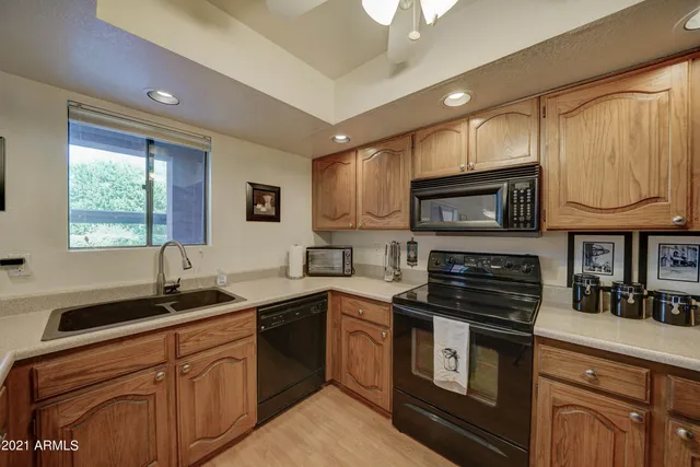 a kitchen with stainless steel appliances granite countertop a sink a stove a microwave cabinets and a window