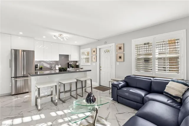 a living room with stainless steel appliances furniture and a kitchen view