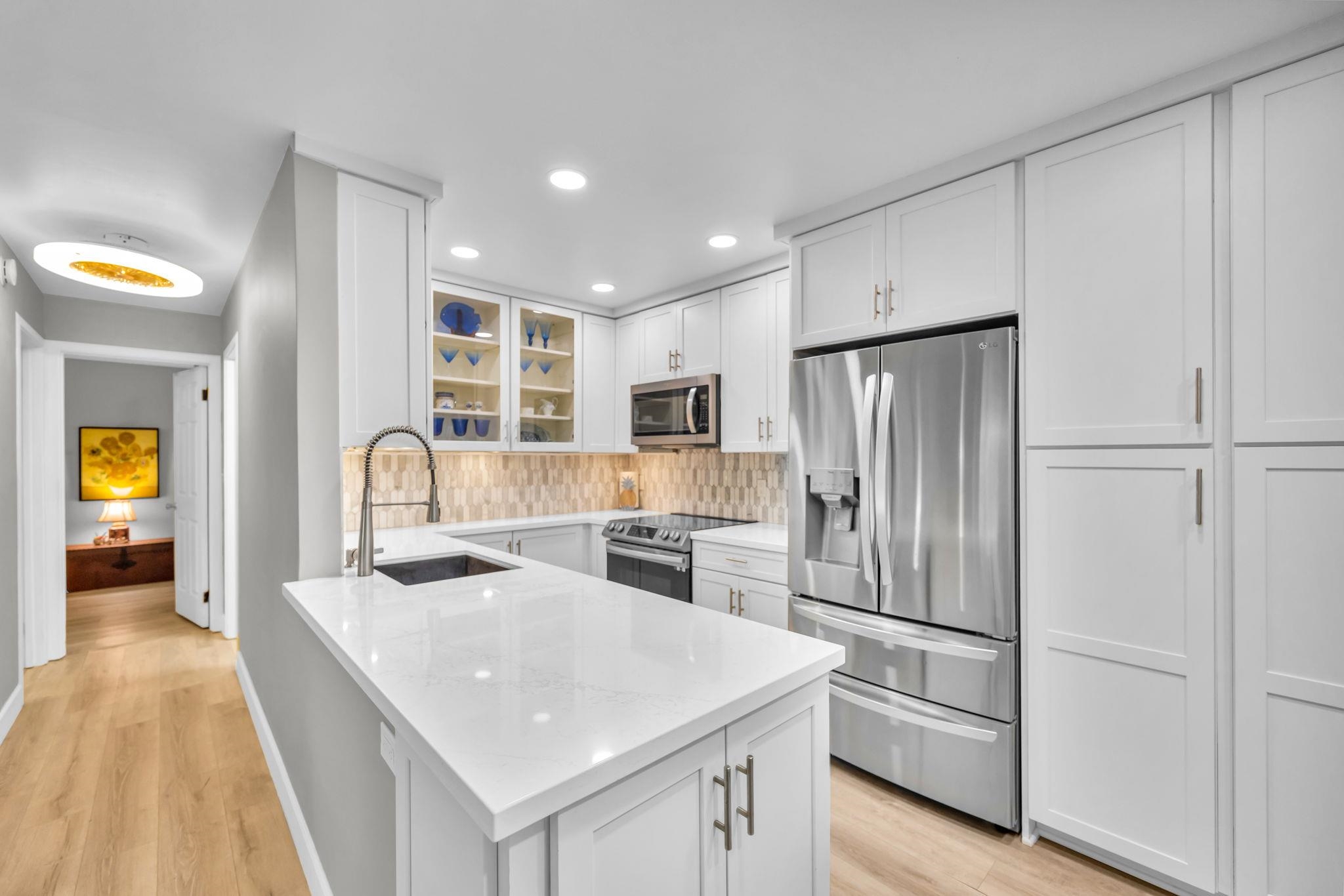 140 Uwapo Road, Unit 36104 Kihei, HI 96753 - Photo 10 of 33 a kitchen with stainless steel appliances granite countertop a refrigerator a stove and a sink with wooden floor