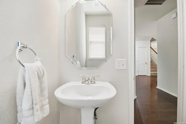 a bathroom with a sink a mirror and wooden floor