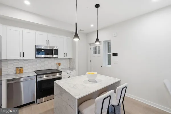 a kitchen with stainless steel appliances a stove a sink a microwave a refrigerator a stove a microwave and island