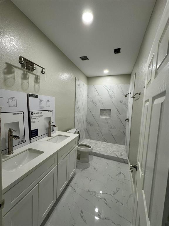 a bathroom with a double vanity sink toilet mirror and shower