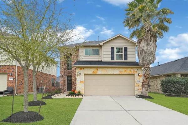 a front view of a house with a garden and trees