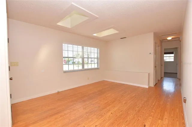 an empty room with wooden floor and windows