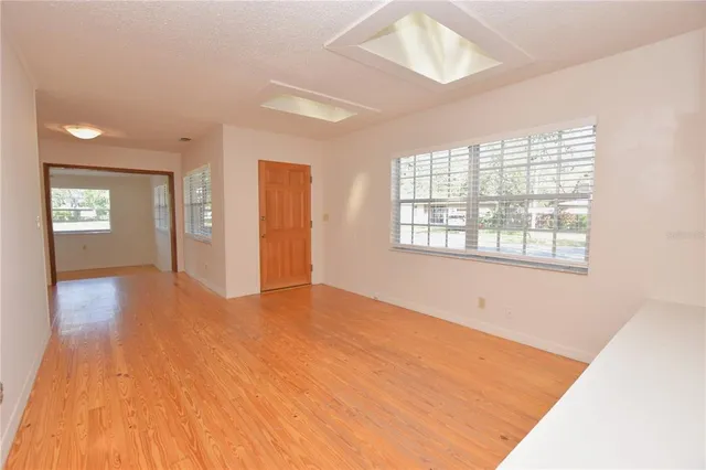 a view of an empty room with window and wooden floor