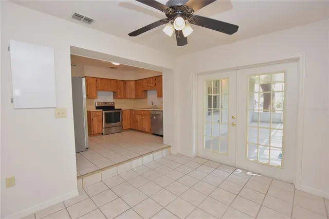 an empty room with chandelier fan and windows